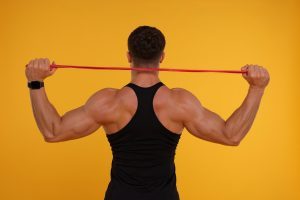 man demonstrating resistance band training with a red band